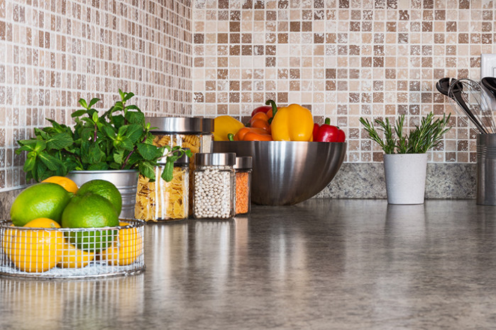 A marble counter-top with various fruits, and jars of food.